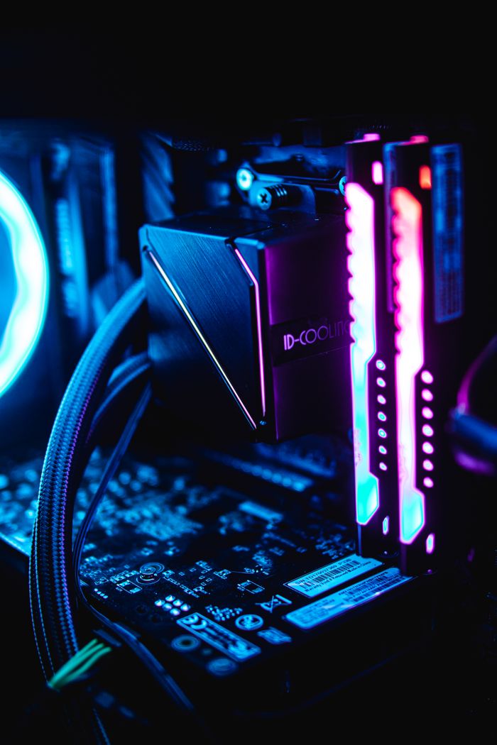 Home Close-up of RGB-lit PC components showcasing vibrant blue and pink hues in a dark setup.