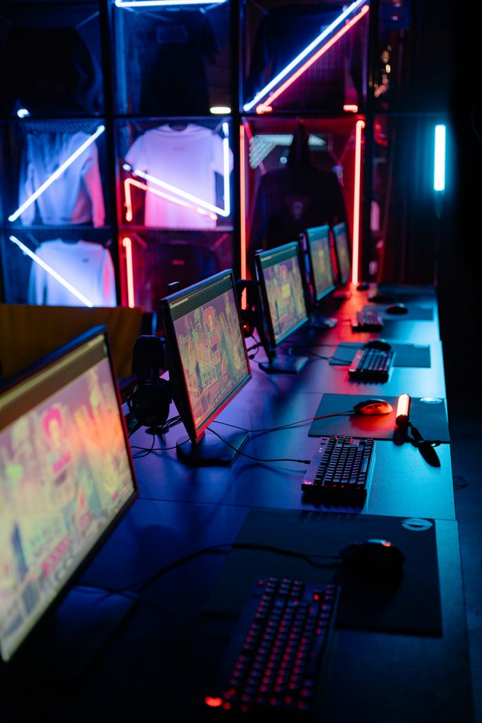 Home A modern cybercafe setup featuring neon lights and aligned computer stations with colorful screens.